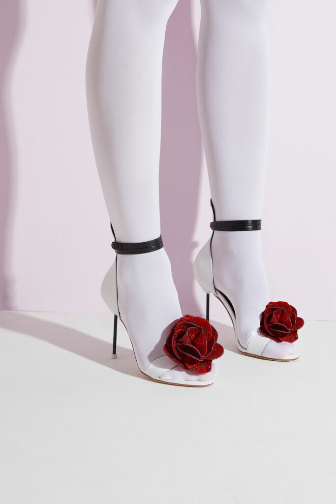 Sandália branca Audrey White Giseli Dias com flor vermelha tridimensional, tiras pretas e salto alto.